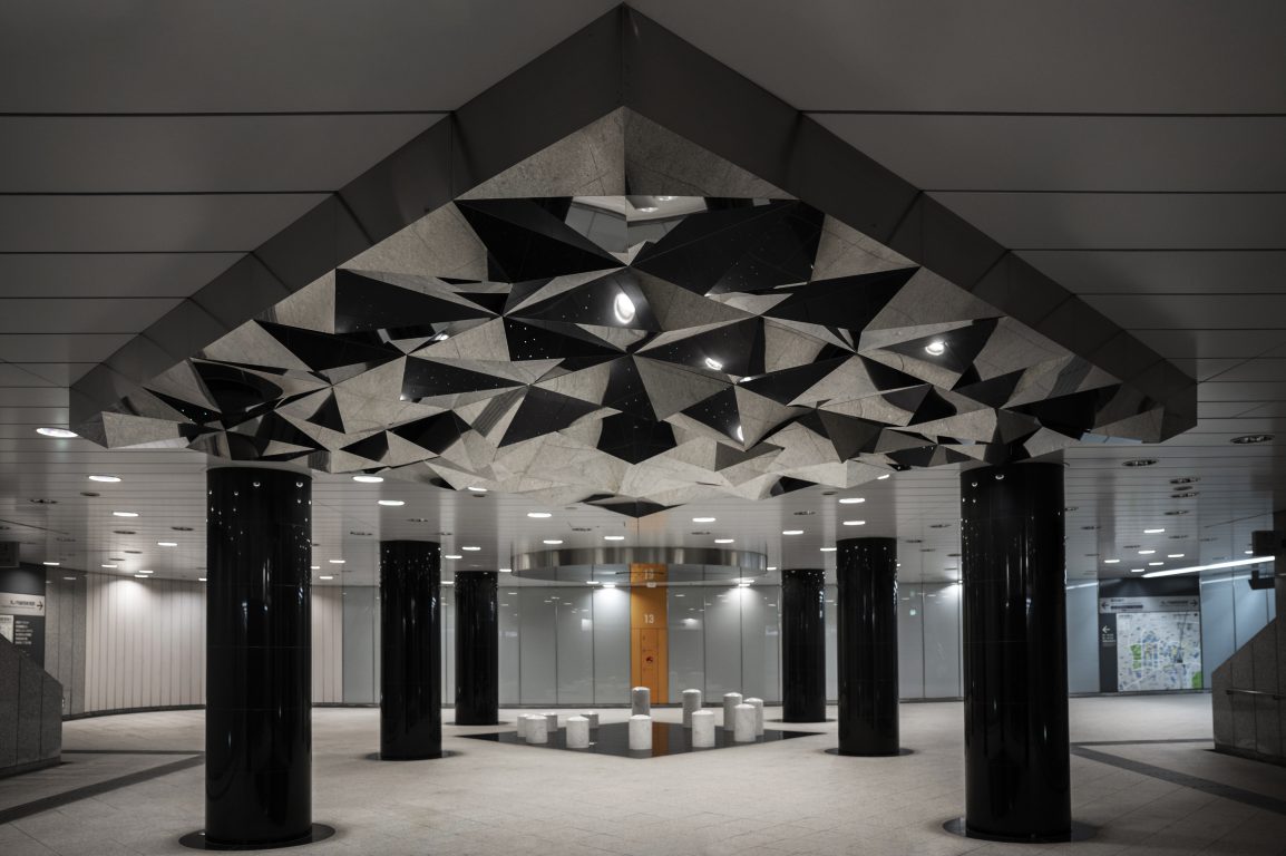 A grid of aluminum ceiling tiles with a metallic finish, featuring intricate patterns and a sleek, reflective surface, installed in a modern interior space.